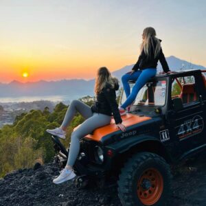 Two women are enjoying the beautiful sunrise from the top of a jeep with Batur Sunrise Jeep Tour.